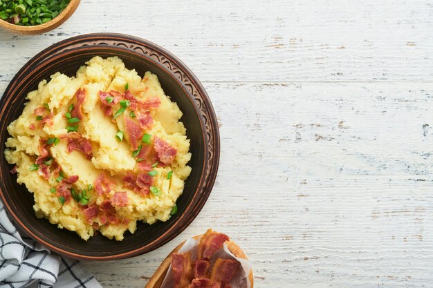 Mashed boiled potatoes Bacon mashed potatoes with green onion pepper and cheddar cheese in bowl on light old wooden backgrounds Delicious creamy mashed potatoes Top view