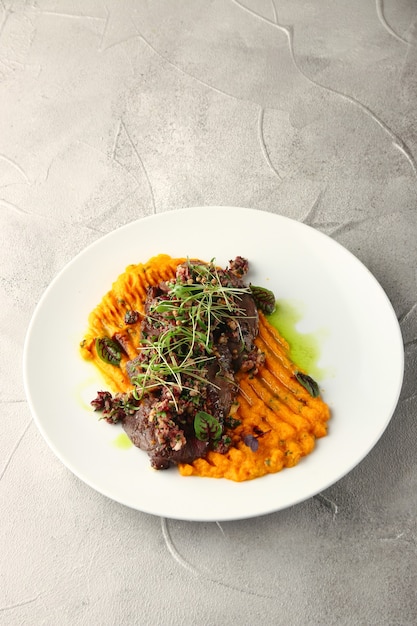 Mashed carrot with beef and green on cement background