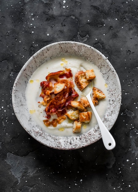 Mashed cauliflower soup with bacon and crackers on a dark
background top view delicious comfort food concept