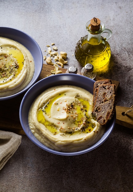 Mashed cauliflower with cashew nuts in plates on the table with rye bread 