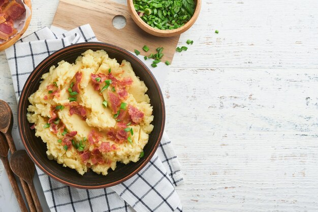 Mashed potatoes Bacon mashed potatoes with green onion pepper and cheddar cheese in bowl on old wooden backgrounds Delicious creamy mashed potatoes Top view