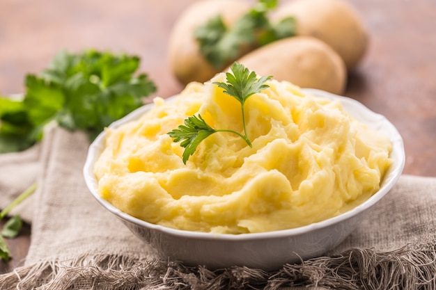 Photo mashed potatoes in bowl decorated with parsley herbs.