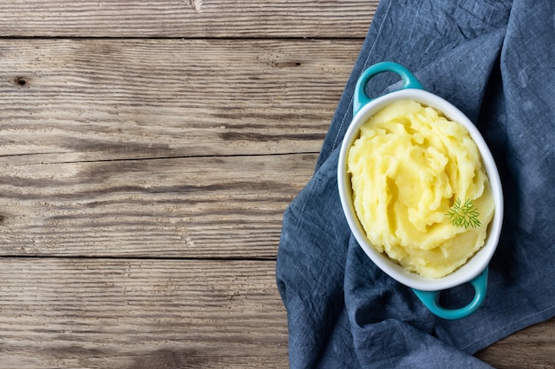 Mashed potatoes in bowl on wooden rustic background. Top view.