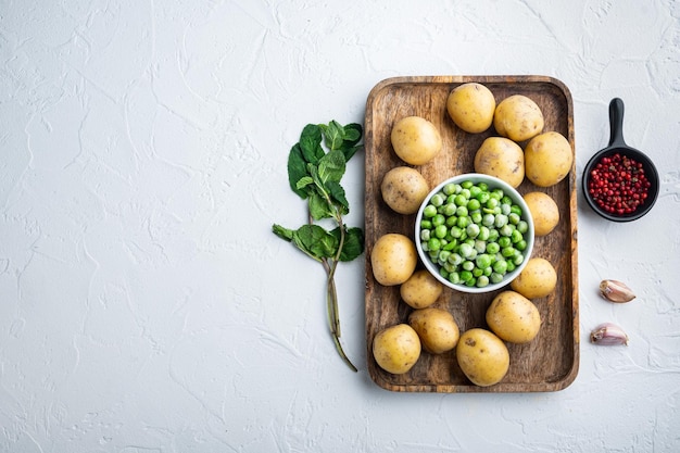 Mashed potatoes ingredients with green pea and mint flat lay on white textured background with space for text