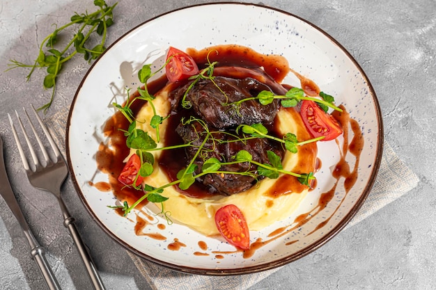 Mashed potatoes with beef in sweet and sour sauce decorated with tomatoes and microgreens