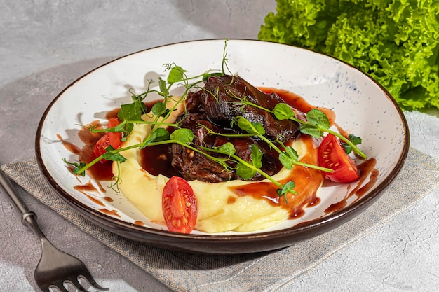 Mashed potatoes with beef in sweet and sour sauce decorated with tomatoes and microgreens