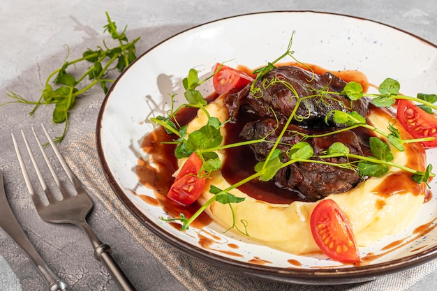 Photo mashed potatoes with beef in sweet and sour sauce decorated with tomatoes and microgreens