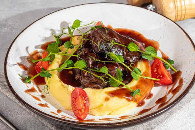 Foto purè di patate con carne di manzo in salsa dolce e acida decorata con pomodori e microgreen