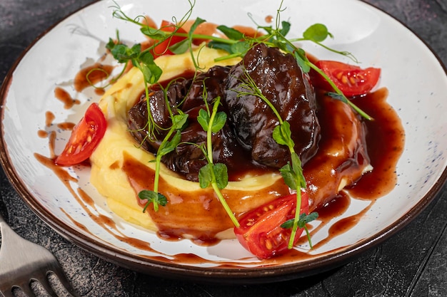 Photo mashed potatoes with beef in sweet and sour sauce decorated with tomatoes and microgreens