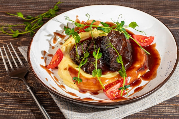 Photo mashed potatoes with beef in sweet and sour sauce decorated with tomatoes and microgreens