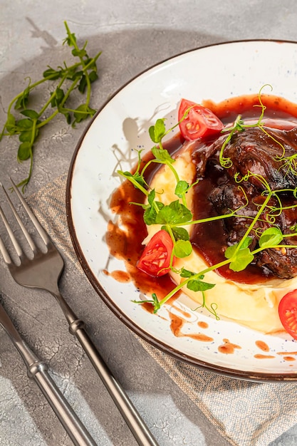 Foto purè di patate con carne di manzo in salsa dolce e acida decorata con pomodori e microgreen