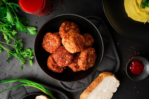 Mashed potatoes with cutlets tomato juice and herbs on a dark background High quality photo