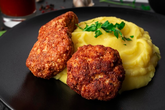 Mashed potatoes with cutlets tomato juice and herbs on a dark background High quality photo