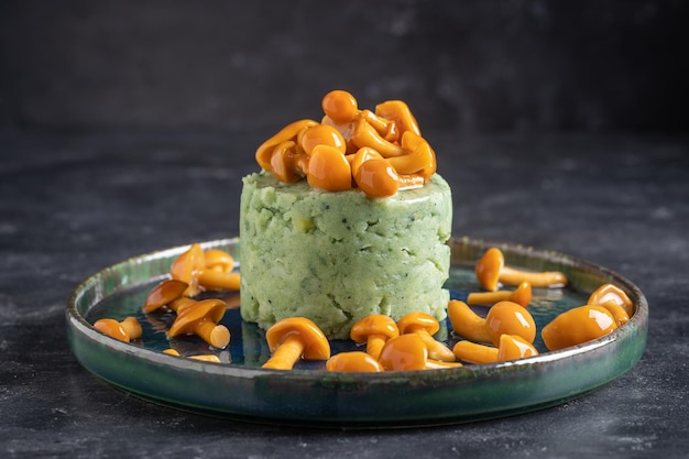 Mashed potatoes with green spirulina and honey mushrooms in a plate