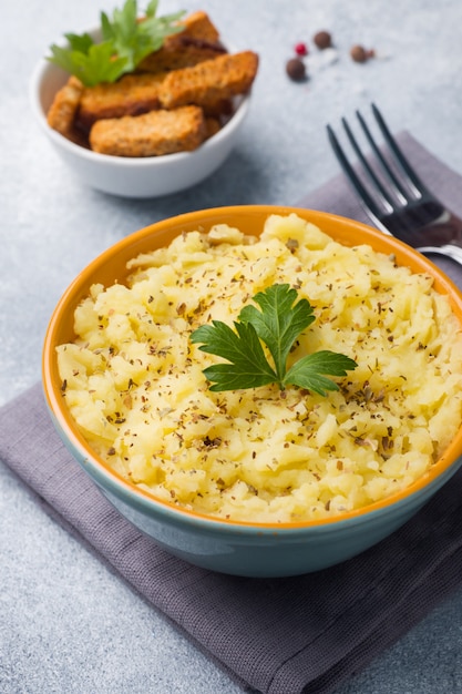 Картофельное пюре с зеленью, гренками и лимоном в тарелке на салфетках.