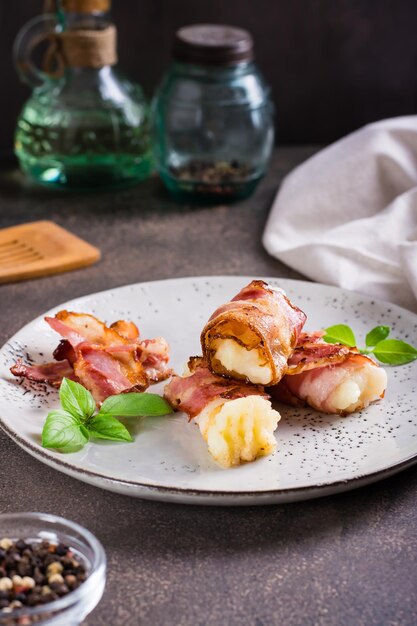 Mashed potatoes wrapped in fried bacon on a plate on the table Vertical view