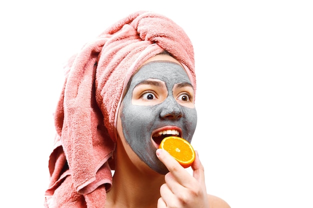 Фото Маска для кожи женщина, девушка кусает апельсин, счастливая и веселая девушка делает маску для кожи лица, изолированное фото