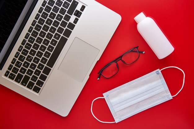 Mask and laptop on a red background. Concept of study, work and business.