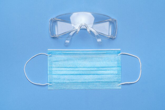 Mask and safety glasses for personal protection on blue baclground.