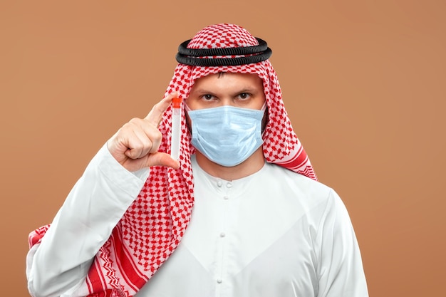 A masked Arab man holds a test tube in a national costume.