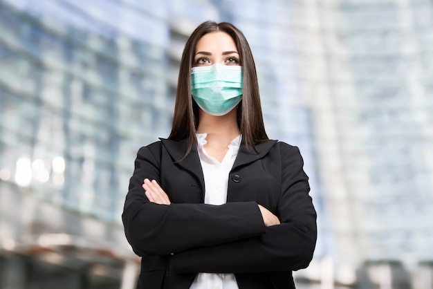 Masked businesswoman in front of her office, coronavirus pandemic and work concept