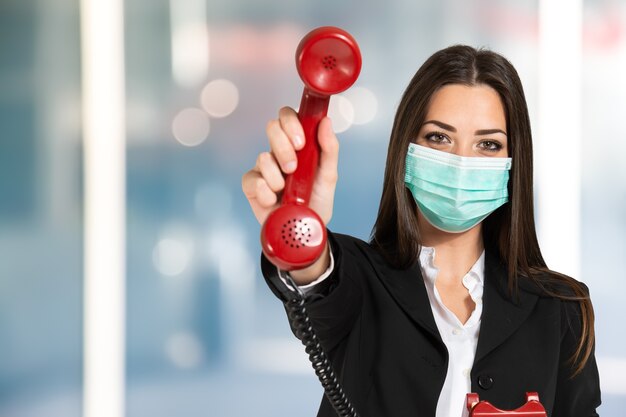 Imprenditrice mascherata che utilizza un telefono vintage durante la pandemia di coronavirus