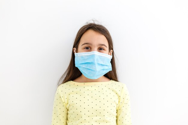 가면을 쓴 아이 - 인플루엔자 바이러스에 대한 보호. pm2.5 보호를 위해 마스크를 쓴 백인 소녀. 생물학 무기. 복사 공간이 있는 회색 배경에 있는 아기. 감염병 유행 감염병 세계적 유행.