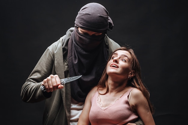 Masked criminal threatening girl with knife