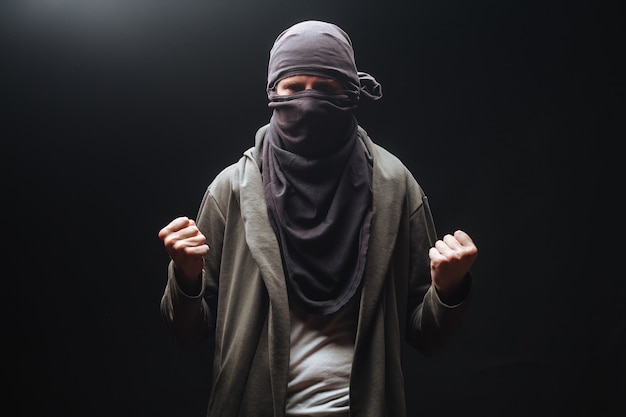 Masked criminals with fists on a dark background