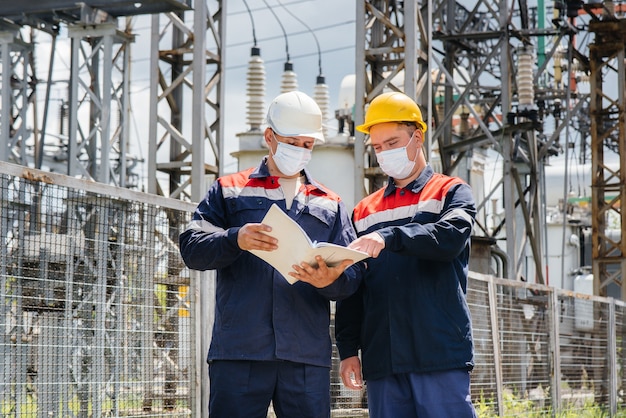 Masked engineers inspect an electrical substation