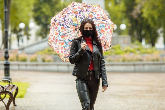 A masked girl is walking along the street.