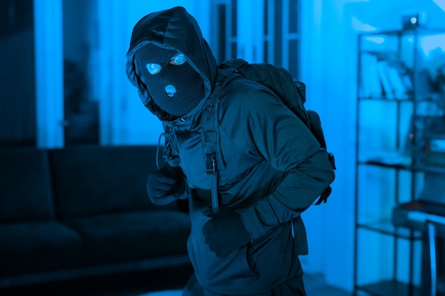 仮面をかぶった男の強盗が屋内で身を隠している