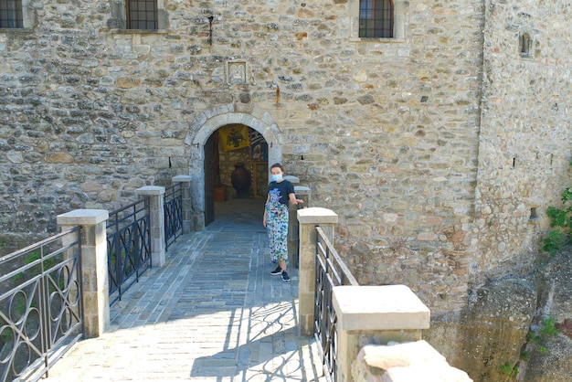 Un turista mascherato entra nella fortezza per un tour della grecia kalabaka