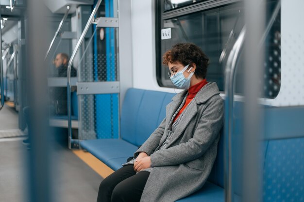 Photo masked woman sleeps sitting on a bench in a subway car