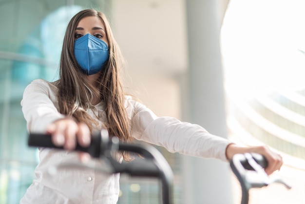 Masked woman using her bike in a modern city