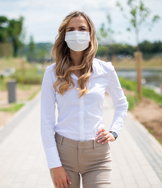 Masked woman walking in a city park during coronavirus emergency