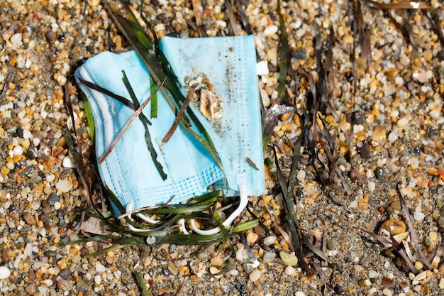 Masker achtergelaten op het strandconcept van een nieuw type milieuvervuiling na COVID19