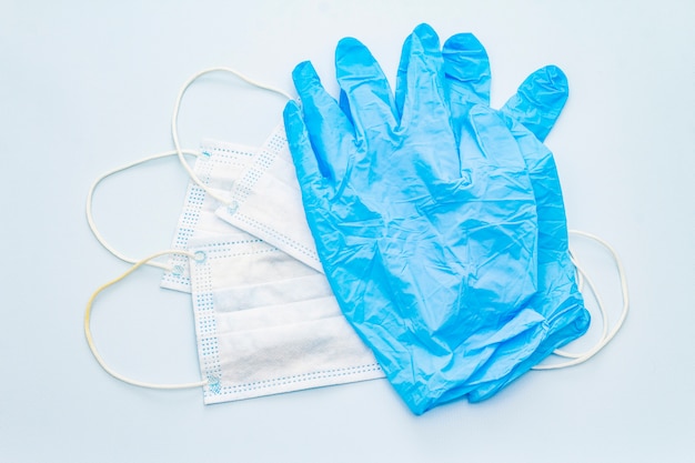 Masker en handschoenen die op blauwe achtergrond wordt geïsoleerd