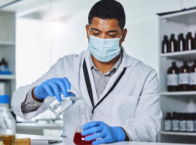 Masker wetenschapper of man met vloeistof in het laboratorium voor medisch onderzoek experiment en of geneesmiddel analyse Gezondheidszorg ppe of handschoenen van arts met bescherming voor chemische vloeistoof of mengsel in testbuis