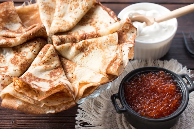 Maslenitsa holiday pancakes with red caviar and sour cream on the table The Russian tradition