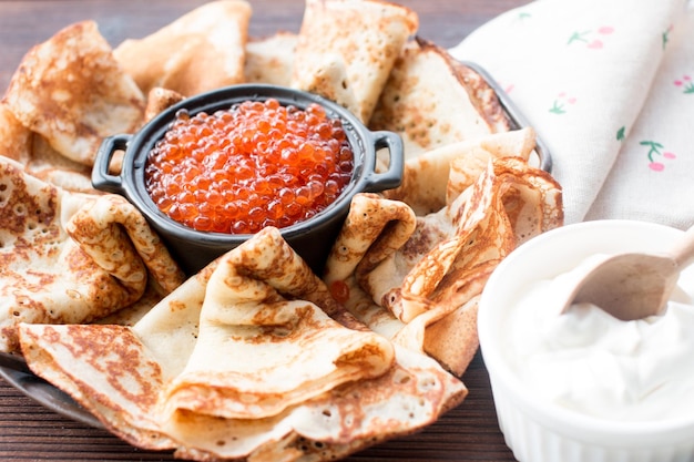 Maslenitsa holiday pancakes with red caviar and sour cream on the table The Russian tradition