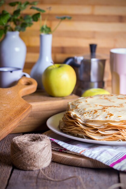 マースレニツァとパンケーキウィーク。ソーサーでサワークリームとロシアの伝統的なパンケーキでいっぱいの料理