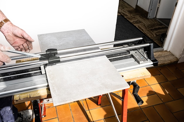 The mason cuts a ceramic tile with a tile cutter