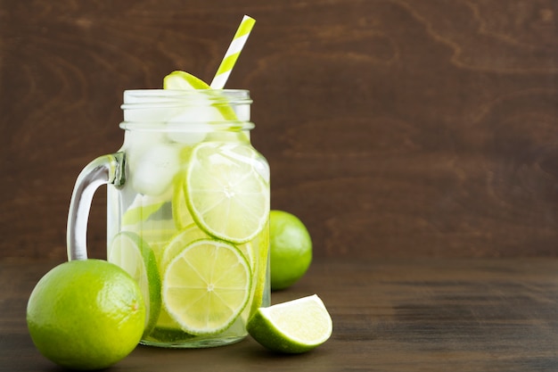 Mason jar glass of lemonade with lime and straw on wooden background-image
