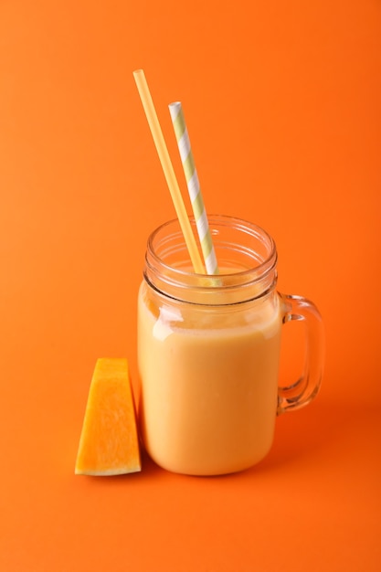 Mason jar of tasty pumpkin smoothie on color surface