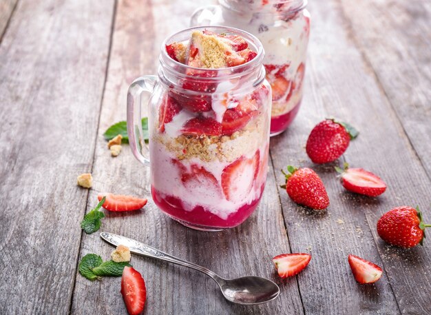 Mason jar of tasty strawberry dessert on wooden table
