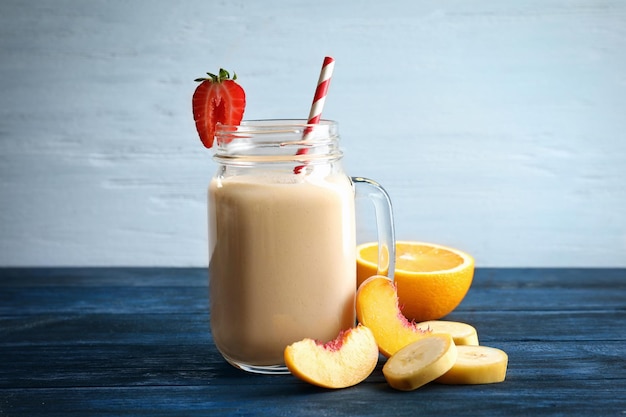 Mason jar with milkshake on wooden table