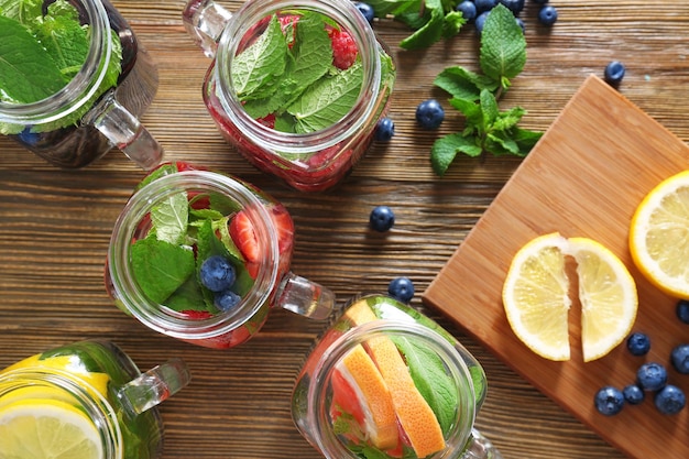 Mason jars of infused water with fruits on wooden table