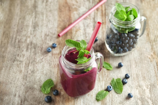 Mason jars with acai juice and berries on wooden table