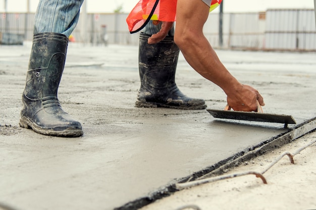 Mason worker leveling concrete with trowels mason hands spreading poured concrete